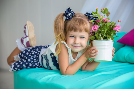 Portrait of a little girl with a pot of flowers. March 8. Mother's Day