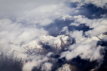 Fototapeta na wymiar View over the clouds from the porthole of an airplane of italian alps mountains