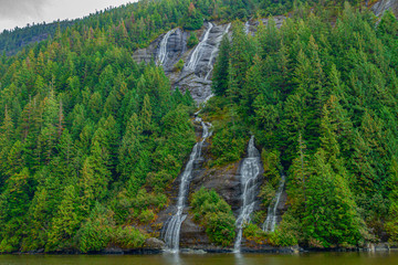 Waterfall flows through the green mountains. Natural source of water.