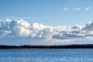 blue sky and big clouds on the sky. A lake with a forest on the horizon and a cloudy sky. summer day at the lake. Maardu, Estonia