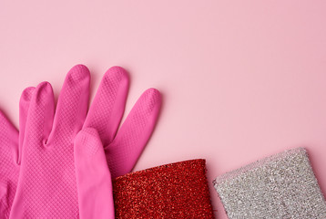 multi-colored kitchen sponge, rubber pink gloves on a pink background