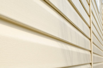 Light beige vinyl siding of the house. Plastic panels texture.