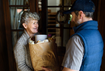Courier delivering shopping to senior woman, corona virus and quarantine concept.