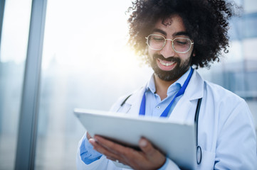 Portrait of male doctor with tablet standing in hospital. Copy space.