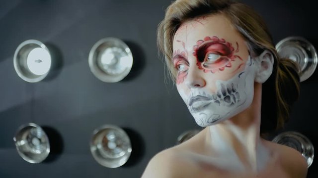 Nice girl with body art tattoo patterned skull chicano style on her face looking at the camera. Halloween party and mexicans death day santa muerte concept