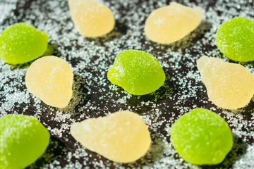 
Multi-colored marmalade and sprinkled sugar on a black background.