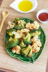 Baked broccoli and cauliflower vegetables with spices on green plate. Vegan healthy diet food concept