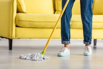 Fotobehang Cropped view of woman mopping floor with mop in living room © LIGHTFIELD STUDIOS