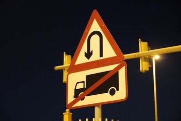U-turn signs on the street at night Is a grain film image. U turn sign after sunset. View of dark, black sky.