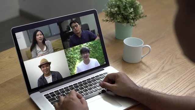 Person using video conferencing technology to his asian friends with laptop in living room during coronavirus situation. 4K resolution.