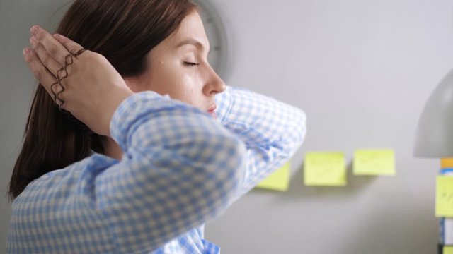 Girl collects hair in ponytail. Young woman in office at workplace collects hair in bun preparing for work day