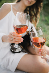 Two glasses of red wine in hand against the background of the sunset