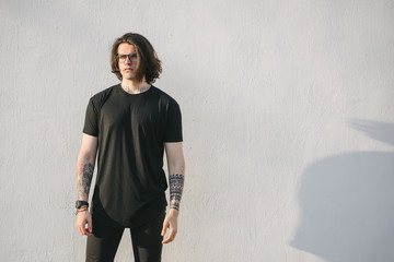Hipster handsome male model with glasses wearing black blank t-shirt and black jeans with space for...