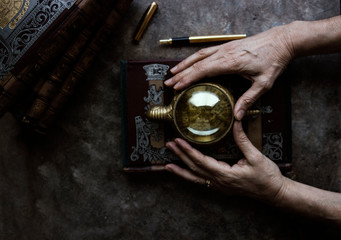 Woman hands with magnifying glass and books.