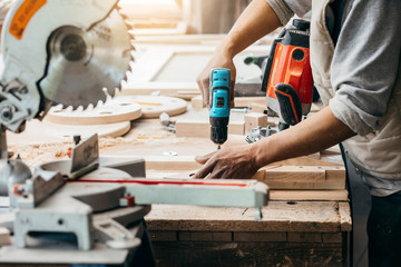Carpenter drills a hole with an electrical drill
