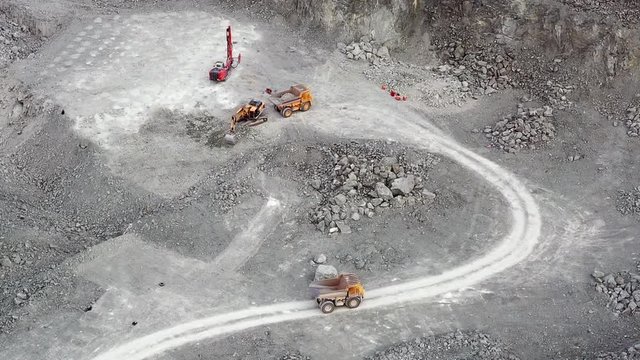 Aerial video view of mining quarry. Excavator loads rock in a dump truck