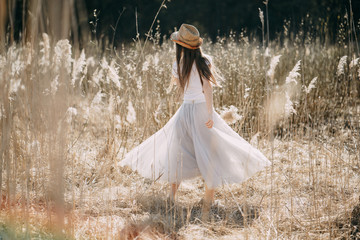 portrait of a girl in a straw hat on the street in the high dry grass