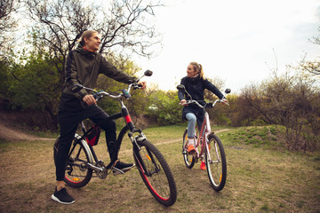 Fototapeta na wymiar Best friends having fun near countryside park, riding bikes, spending time healthy. Calm nature, spring day, positive emotions. Sportive, active leisure activity. Traveling or walking together.