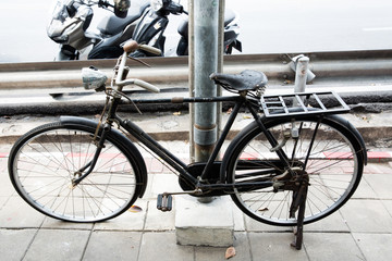 Obraz premium Black antique bicycle parked on a foot bath beside an electric pole