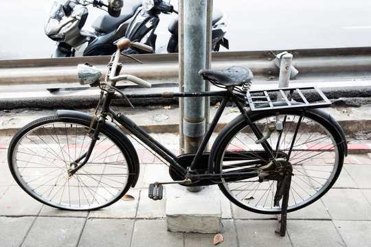Black antique bicycle parked on a foot bath beside an electric pole