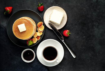 Obraz na płótnie Canvas The concept of a delicious breakfast. Coffee and mini pancakes with strawberries, bananas, nuts in a plate on a stone background with copy space for your text