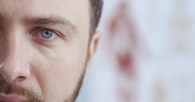 Close-up portrait of half face of the handsome blue-eyed doctor with beard seriously confidently looking straight to the camera. Сoncept of pandemic, modern medicine remotely.