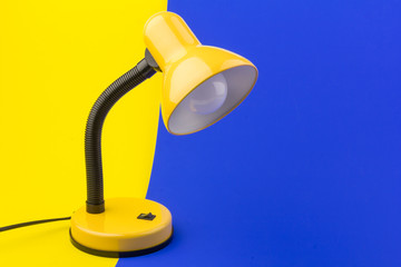 Obraz na płótnie Canvas Yellow desk lamp isolated on yellow and blue background