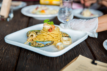 Seafood spaghetti in a white plate on an old wooden table