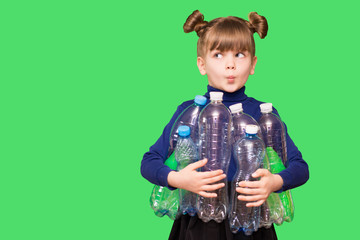 Photo of confused funny little girl holding plastic bottles and looking at camera isolated over...