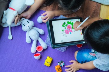 Children drawing image with tablet computer pen while playing in house