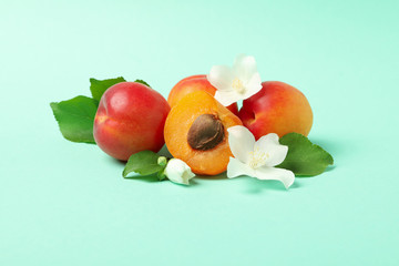 Tasty apricots and leaves on mint background, space for text