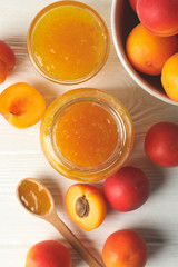 Composition with tasty apricots and jam on white wooden table