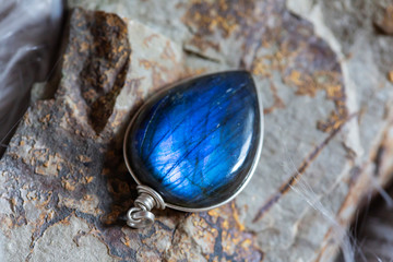 Beautiful labradorite mineral stone pendant on rocky background