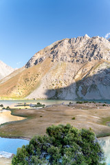 The Pamir range view and peaceful campsite on Kulikalon lake in Fann mountains in Tajikistan. Amasing colorful reflection in pure ice lake.