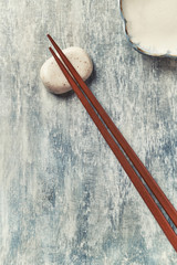 Wooden chopsticks and chopstick rest on rustic wooden background. Top view. Copy space.	