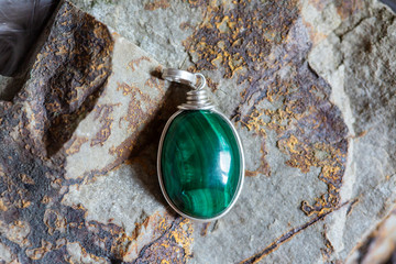 Beautiful malachite mineral stone pendant on rocky background