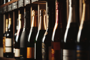 Underground cellar with elite sparkling wine on shelves, close up horizontal photo.