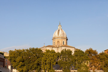 ROME, ITALY - 2014 AUGUST 19. Church dome above the green trees in evening light.