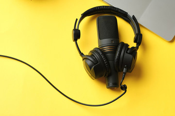 Flat lay composition with Microphone for podcasts  and black studio headphones on yellow background, learning online education concept.