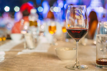 Glass of Red Wine on the food table with Lights Bokeh at night background.