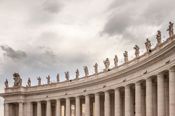ROME, ITALY - 2014 AUGUST 19. St. Peter's Basilica, Group of statues of Peter's Square Colonnade with rainy clouds on background, Vatican city state.