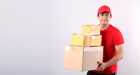 Image of a happy young delivery Asian man in red cap standing with parcel post box isolated over white background in studio With copy space.