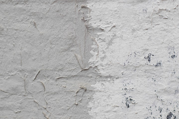 The old rough street wall is painted in white and gray with dark splashes. There is a place for text. A photo was taken close-up for your design.