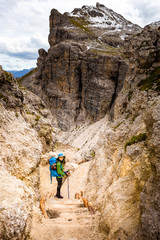 Fototapeta premium Tourist woman hiking mountain alpine canyon trail cliffs, South Tyrol, Italy.