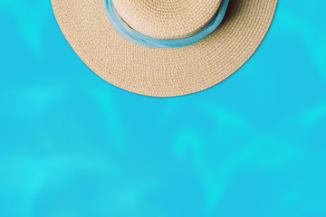 Fototapeta na wymiar Top view of straw beach hat with blue scarf on water background. Minimal summer concept with copy space.