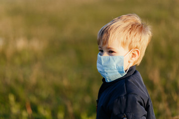 Little blonde boy wearing the medicine mask outside