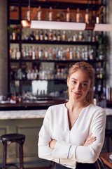 Portrait Of Confident Female Owner Of Restaurant Bar Standing By Counter
