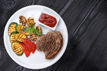 grilled steak, zucchini, on a white plate and black background