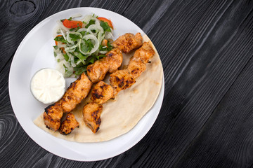 grilled meat on pita bread with salad on a black wooden background