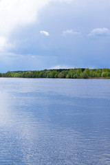 Stormy sky reflected in the river and forest in the background. Before the rain